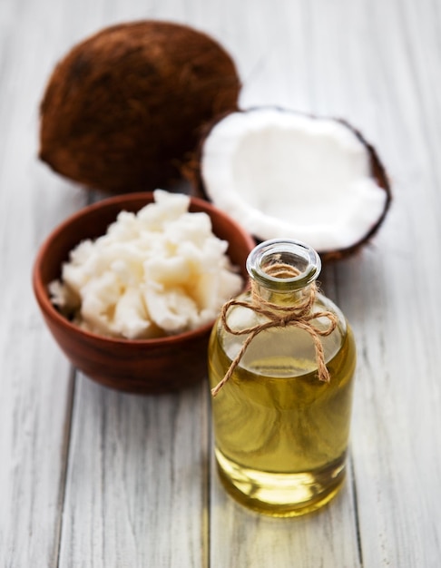 Huile de coco fraîche et noix de coco sur une vieille table en bois