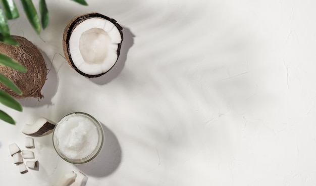 Huile de coco et noix de coco sur fond de béton blanc, l'ombre qu'il laisse d'un palmier sur la table. Mise en page avec espace de copie. Huile de noix de coco biologique pour spa et soins de santé