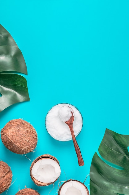 L'huile de coco et les noix de coco sur un fond avec des feuilles tropicales