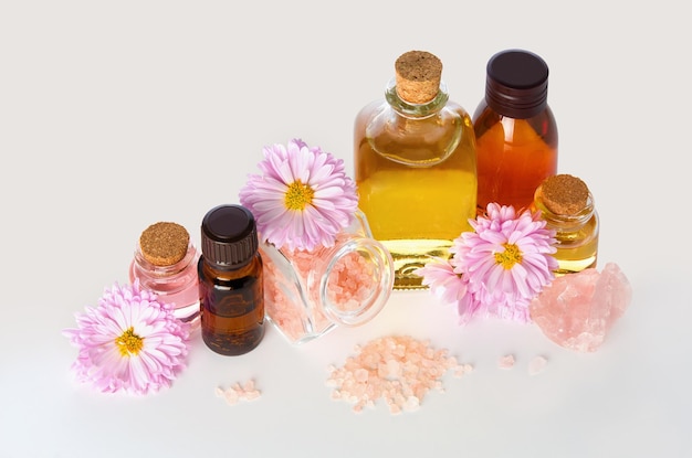 Huile essentielle d'aromathérapie dans des flacons en verre médical avec des fleurs de chrysanthème et du sel de bain