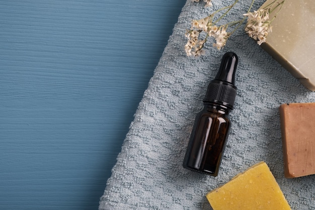 huile essentielle d'arôme dans une bouteille en verre serviette de savon à la main sur un bureau en bois bleu