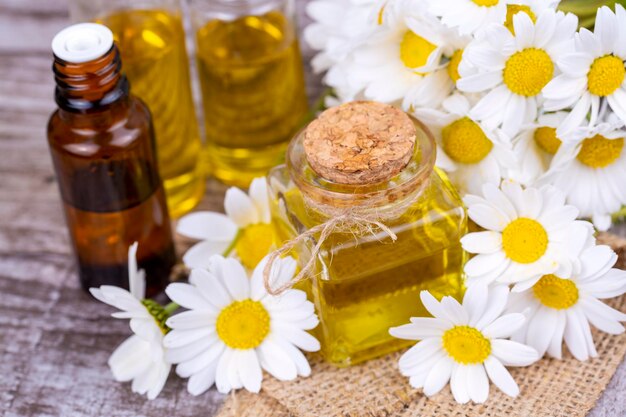 Huile essentielle en bouteille de verre avec fleurs de camomille fraîches, soin de beauté.