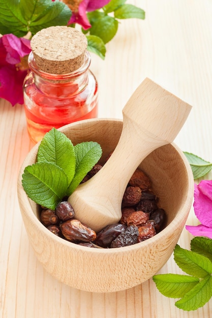 Huile essentielle dans une bouteille en verre de baies d'églantier séchées et de fleurs d'églantier