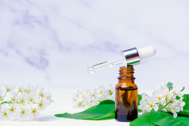 Huile essentielle de fleur de pommier dans une bulle avec une pipette sur un espace de copie de fond en marbre blanc