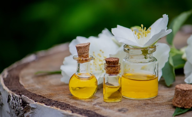 Huile essentielle et fleurs de jasmin sur un fond en bois. Procédures cosmétiques. Mise au point sélective