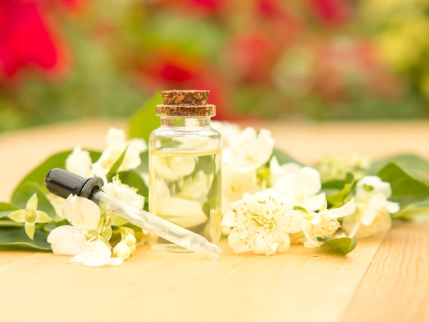 Huile essentielle de jasmin dans une bouteille en verre sur fond de fleurs de jasmin sur une table en bois