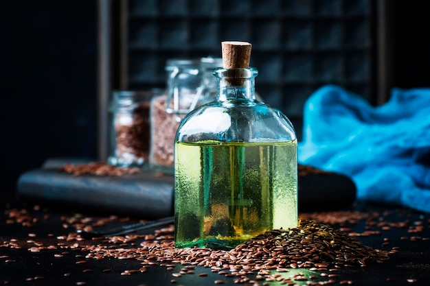 Huile de lin ou de lin dans une bouteille en verre et graines mise au point sélective sur fond sombre