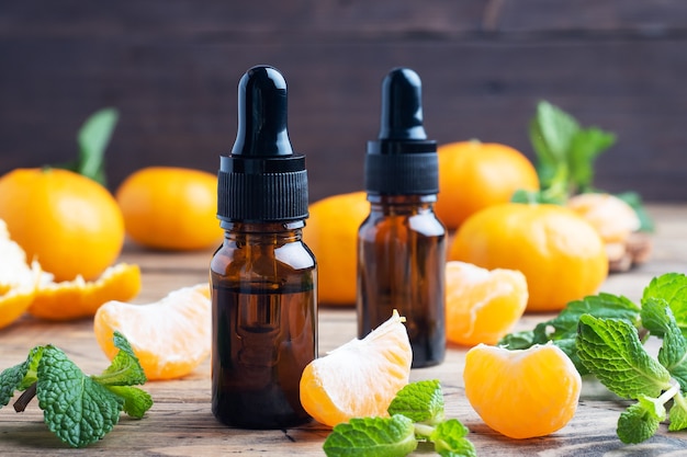 Huile de mandarine aromatique dans une bulle sombre, huile cosmétique de mandarine sur une table en bois, copiez l'espace.