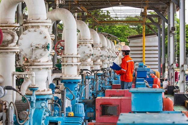 Huile moteur de la pompe d'inspection des travailleurs masculins dans les longs tuyaux en acier et le coude de tuyau dans l'usine d'huile de la station pendant la vanne de raffinerie du pipeline d'enregistrement de contrôle visuel