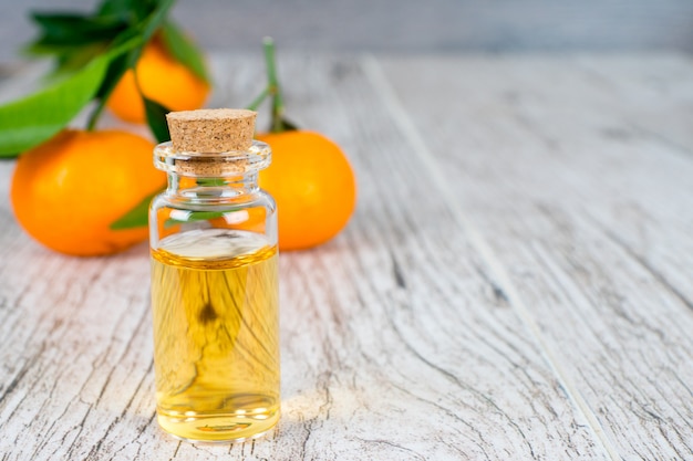 Huile naturelle de mandarine en bouteille sur table rustique en bois blanc