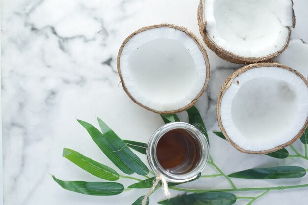 huile de noix de coco et noix de coco sur une surface blanche