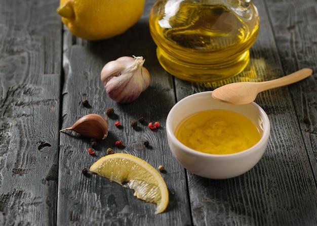 L'huile d'olive à l'ail et au citron dans un bol blanc sur une table noir foncé. Vinaigrette pour salade diététique.