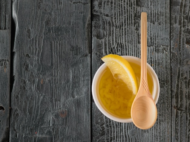 L'huile d'olive à l'ail et au citron dans un bol blanc sur une table sombre. Vinaigrette pour salade diététique. La vue d'en haut.