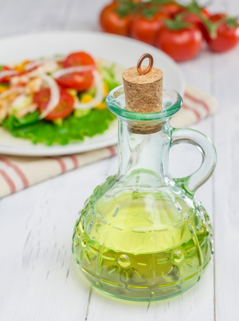 L'huile d'olive dans le bocal en verre avec salade et tomates sur fond