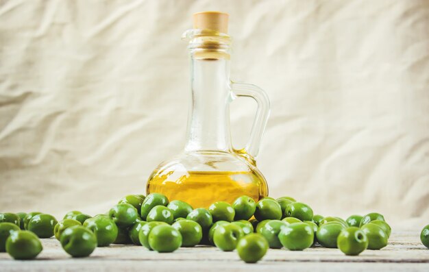 L&#39;huile d&#39;olive dans une bouteille transparente sur un fond en bois. Mise au point sélective.