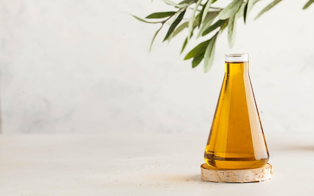 L'huile d'olive dans un flacon en verre sur le fond d'une branche d'olivier le concept d'une alimentation saine copie s...