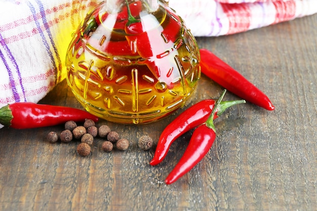 Huile d'olive infusée naturelle faite maison avec des piments rouges et des épices dans une bouteille en verre sur fond de bois