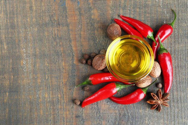 Huile d'olive naturelle faite maison avec des piments rouges et des épices sur fond de bois