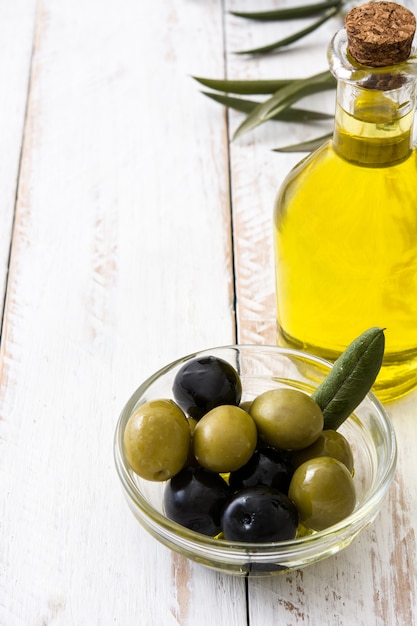 Photo huile d'olive vierge dans une bouteille en cristal sur une table en bois blanc