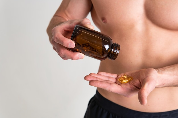 L'huile de poisson est consommée par un homme entre les mains de flacons et une capsule de pilule de bouteille en verre oméga sain