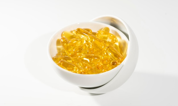 L'huile de poisson Oméga 3 sur fond blanc supplément de vitamine D jaune gélules macro shot