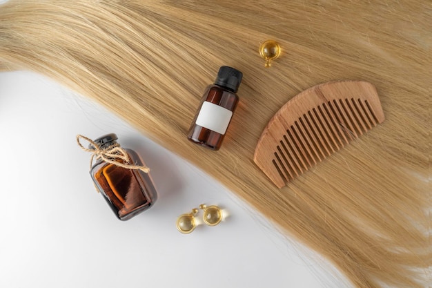 Une huile de soin des cheveux ou un sérum dans des capsules dorées posées sur une mèche de maquette de marketing de produits pour cheveux blonds Un concept de soins capillaires dans un salon ou à la maison