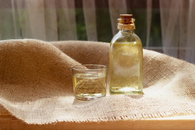 Huile végétale dans un verre de bouteille sur fond de toile de jute