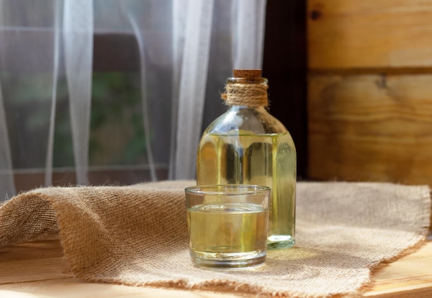 Huile végétale dans un verre de bouteille sur fond de toile de jute