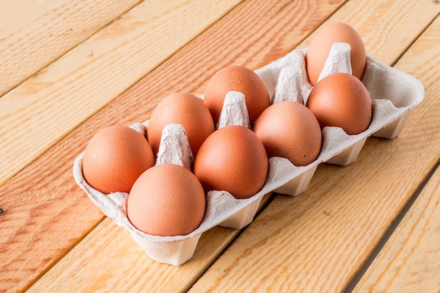 Huit œufs en boîte sur une table en bois
