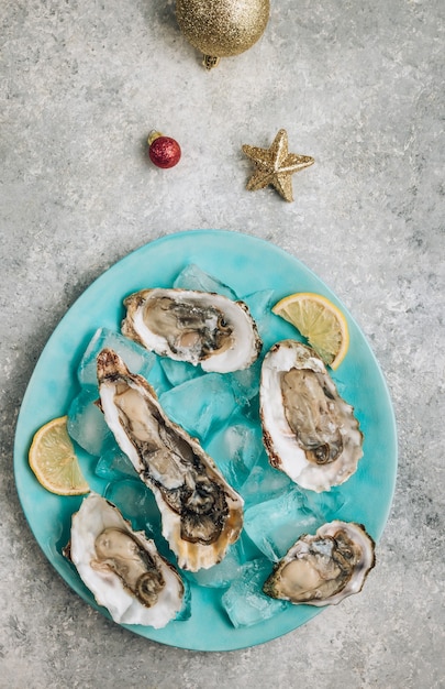 Photo huîtres au citron, glace et vin blanc sur fond de béton avec un décor festif. dîner de noël