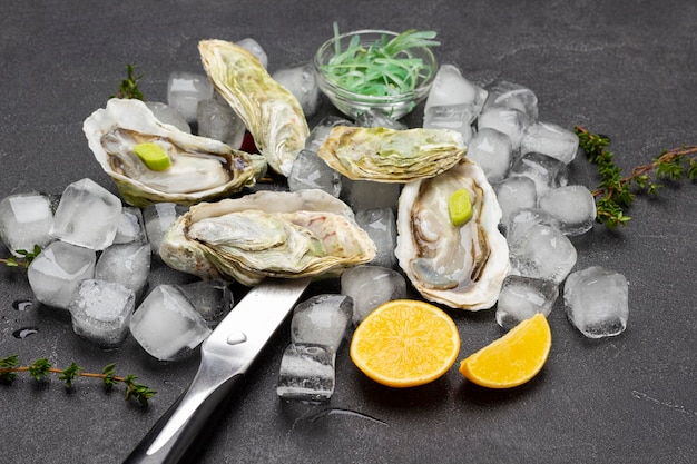 Huîtres en coquilles sur tas de glace Couteau tranches de citron brins de thym sur table Vue de dessus Fond noir