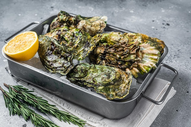 Huîtres fraîches fermées, fruits de mer crus au citron et glace dans un plateau en acier. Fond gris. Vue de dessus.