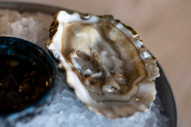 Les huîtres fraîches sur les moitiés de la coquille sont servies dans une assiette avec des citrons glacés et de la sauce Le concept d'une nutrition saine