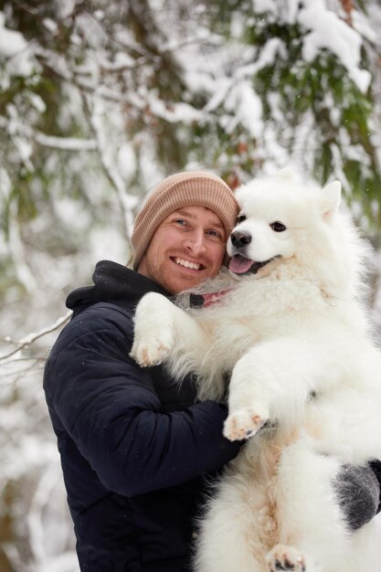 Un humain et un chien sont les meilleurs amis L'homme et le chien se promènent dans la forêt enneigée en hiver dans la neige profonde par une journée ensoleillée