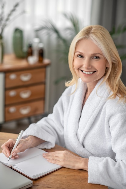 Humeur créative. Belle femme mignonne en blanc assis à la table