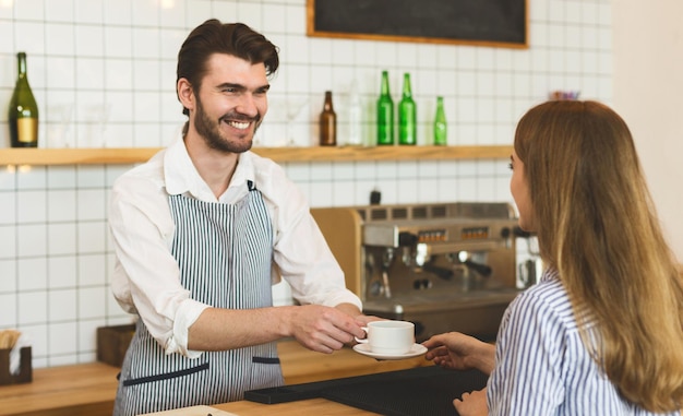 Humeur matinale. Serveur donnant un café aromatique à une fille et lui souriant largement