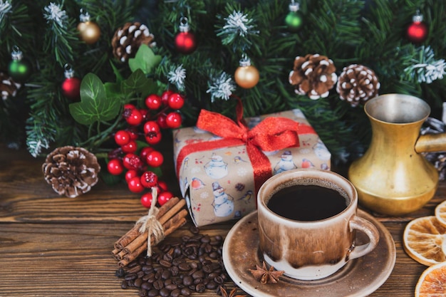 L'humeur de Noël, l'atmosphère des fêtes, la tasse rouge de café, les branches de sapin avec des cônes.