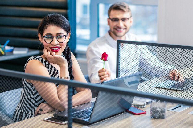 Humeur rêveuse. Mignon femme aux cheveux longs se penchant les coudes sur la table tout en regardant de côté