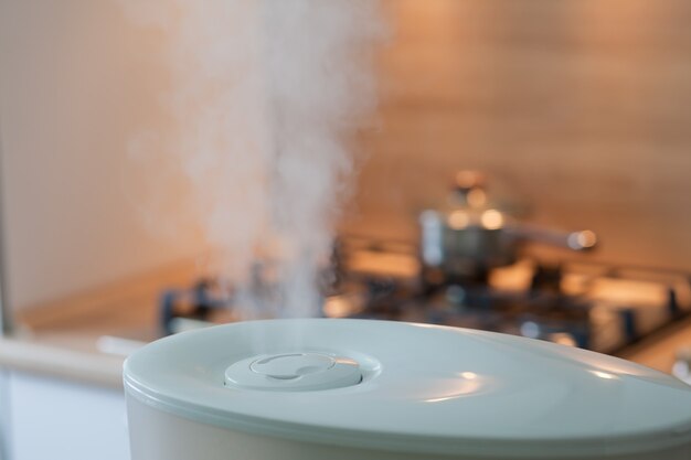 Photo humidificateur diffusant de la vapeur dans la cuisine avec casserole sur le four