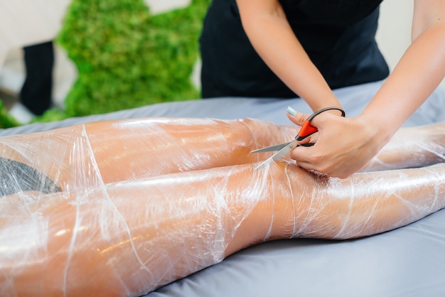 L'humidité et la sueur après un enveloppement de cosmétologie d'une jeune fille dans un salon de beauté