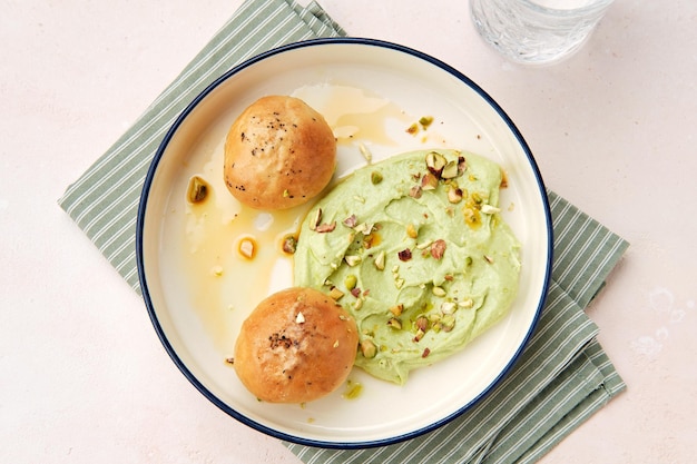 Hummus avec deux pains d'ail sur une belle assiette blanche garnie de noix hachées à rayures de cuisine