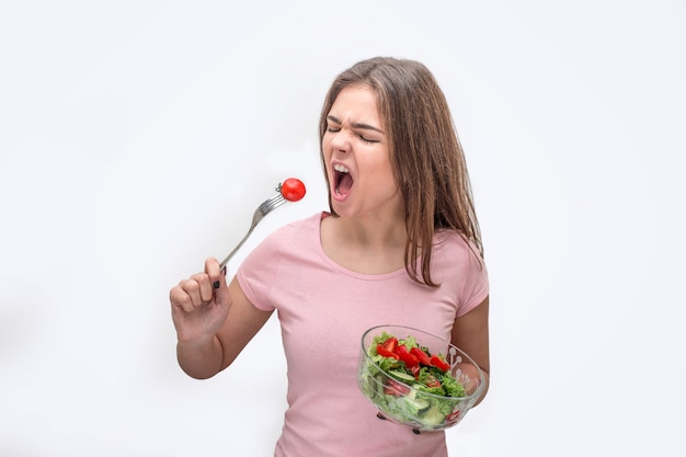 Hungry jeune femme va manger de la tomate sur la fourche