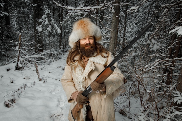 Hunter en vêtements vintage avec des armes à feu se faufile à travers la forêt