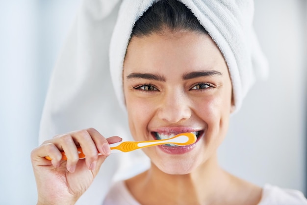 L'hygiène buccale vient en premier Portrait d'une belle jeune femme se brosser les dents dans la salle de bain à la maison