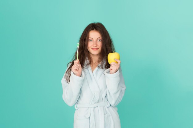 Hygiène bucco-dentaire Femme peignoir tenir brosse à dents et pomme Hygiène personnelle Fille se nettoyant les dents Fraîcheur et propreté Garder les dents saines Habitudes saines Se brosser les dents tous les matins Soins dentaires