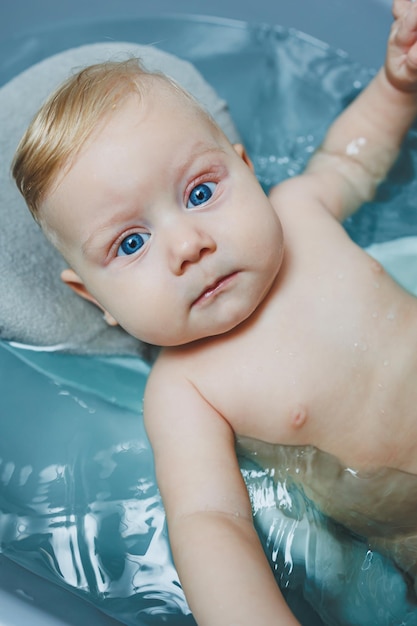 Hygiène des nouveau-nés et des enfants Le bébé est allongé sur un support et se baigne dans une baignoire Baigner un nouveau-né dans un bain
