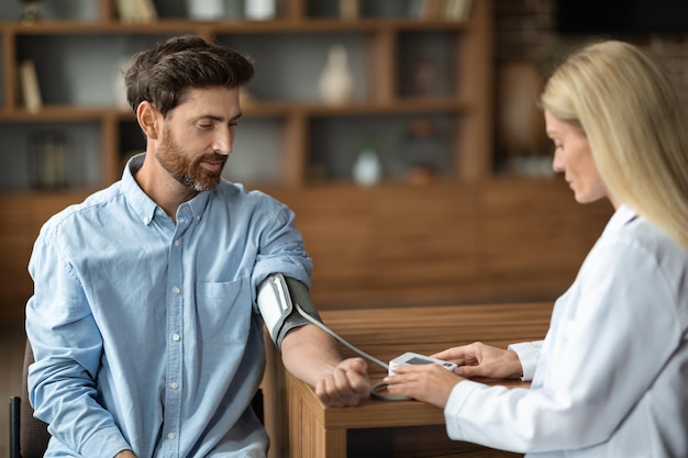 Hypertension Female Doctor Measuring Arterial Blood Pressure Of Male Patient In Clinic