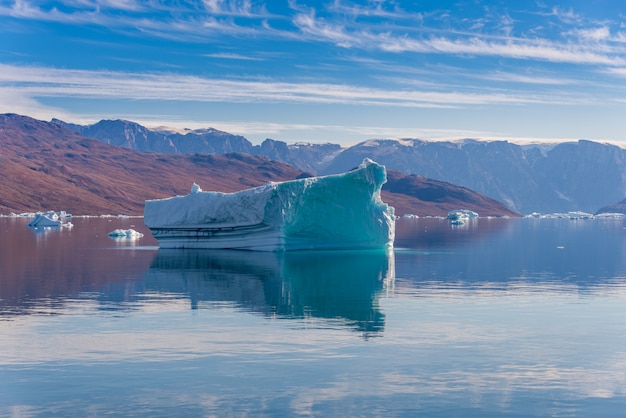 Iceberg dans le fjord du Groenland avec reflet dans une eau calme. Temps ensoleillé. Heure d'or.