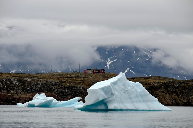 Iceberg avec maisons typiques du Groenland derrière