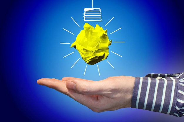 Icône d'ampoule faite avec du papier froissé et un concept de créativité d'idée de main humaine